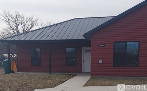 A red house with a black roof and a white door.