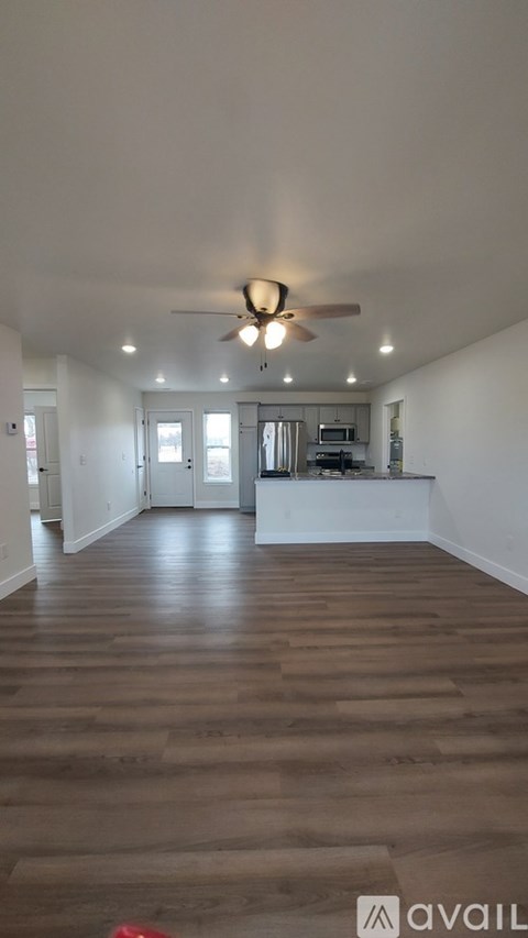 A spacious room with wooden flooring and a ceiling fan.