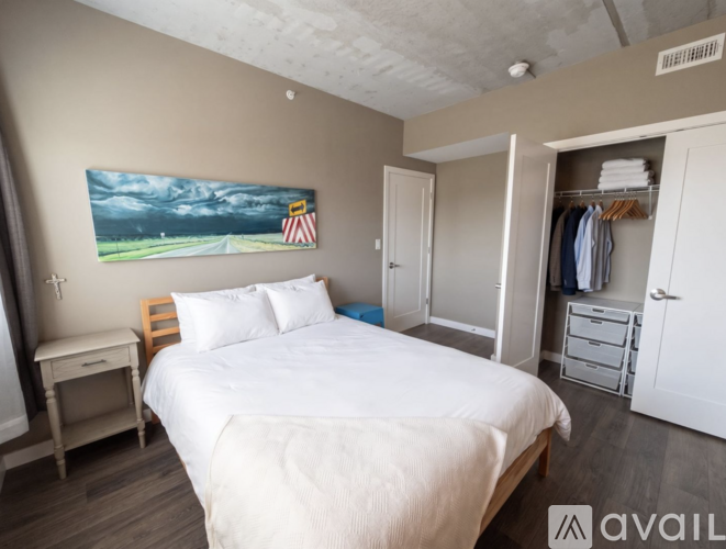 A bedroom with a bed, a nightstand, and a painting on the wall.