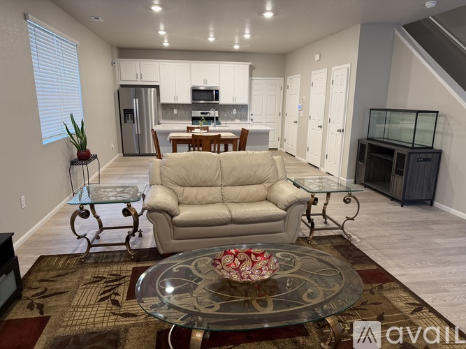 A living room with a glass coffee table and a beige sofa.