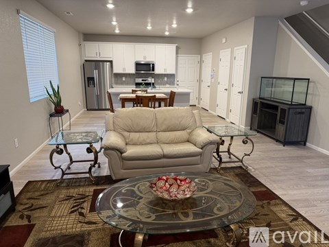 A living room with a glass coffee table and a beige sofa.