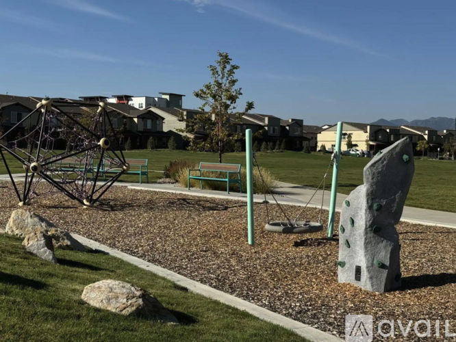 A playground with a swing set and a large rock in the foreground.