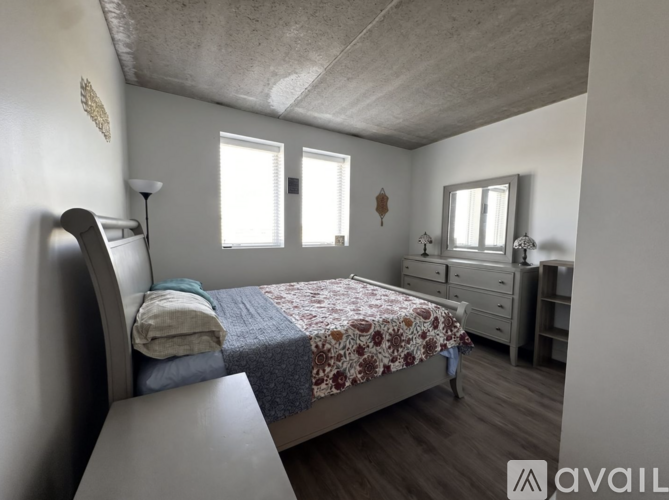 A bedroom with a bed, dresser, and window.