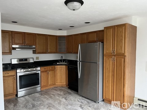 A kitchen with wooden cabinets and a stainless steel refrigerator.