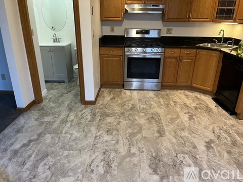 A kitchen with a marble floor and wooden cabinets.