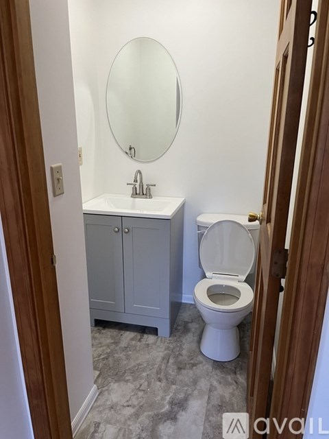 A bathroom with a toilet, sink, and mirror.