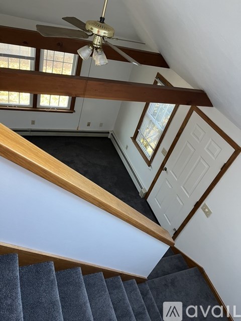 A staircase with a wooden handrail and a ceiling fan.