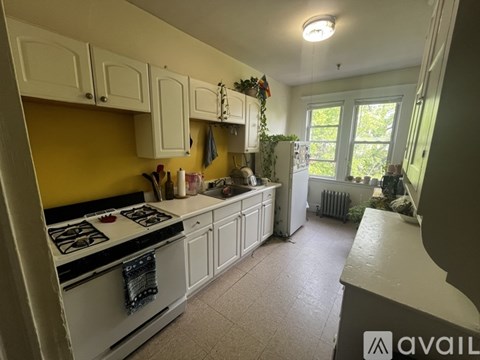 A kitchen with a yellow wall and white cabinets.