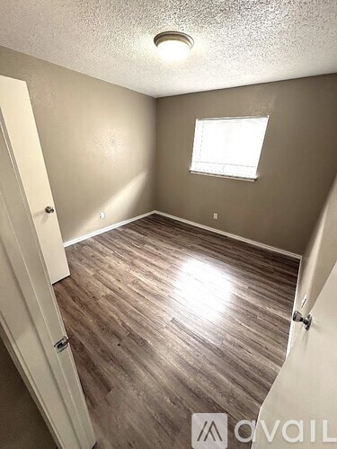 A room with a window and wooden flooring.