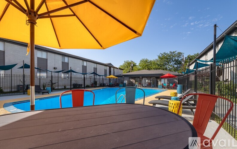 A yellow umbrella shades a table in front of a pool.