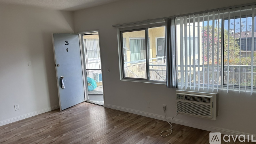 A room with a door numbered 26 and a window with a view of a balcony.