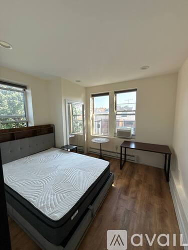 A bedroom with a large bed and a small table by the window.