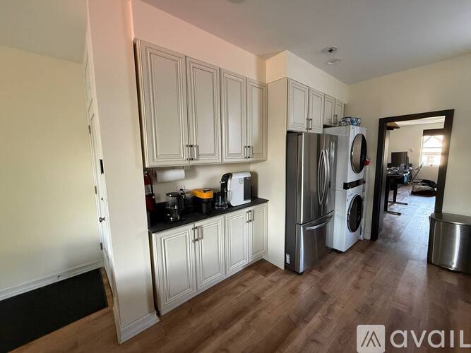 A kitchen with white cabinets and a stainless steel refrigerator.