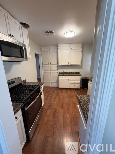 A kitchen with white cabinets and a black stove top oven.