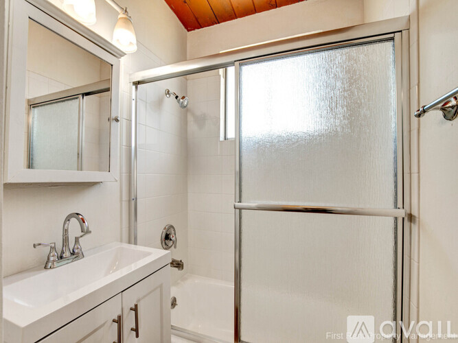 A white bathroom with a sink, mirror, and shower.