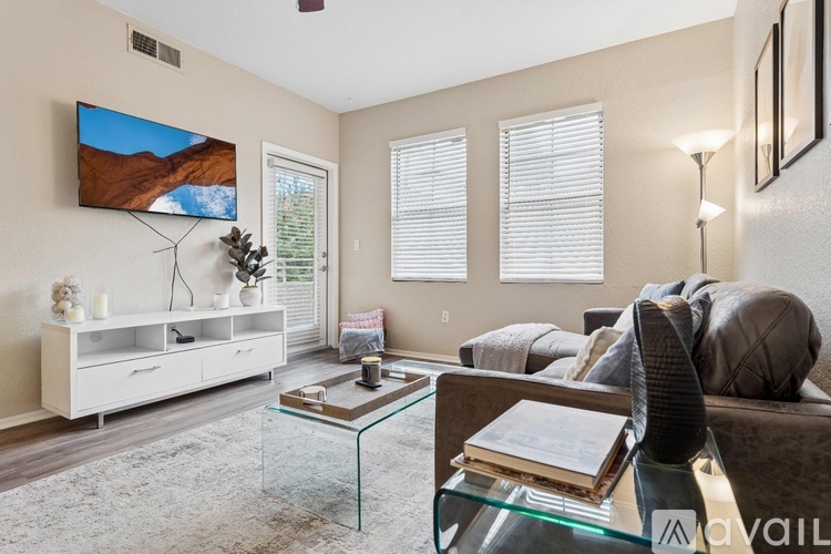A living room with a glass coffee table and a flat screen TV mounted on the wall.
