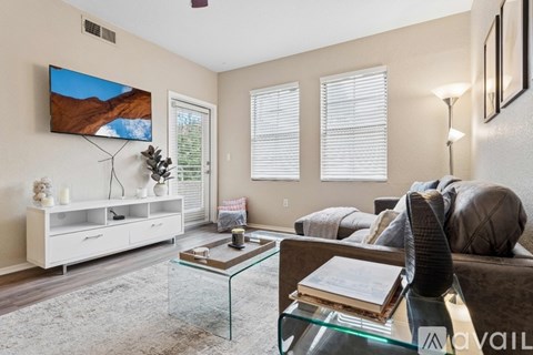 A living room with a glass coffee table and a flat screen TV mounted on the wall.