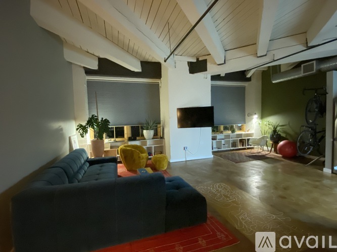 A living room with a blue couch and a red rug.