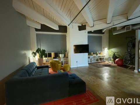 A living room with a blue couch and a red rug.