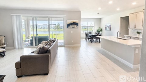 A modern living room with a large couch and a kitchen area in the background.