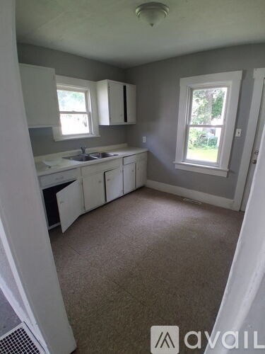 A kitchen with white cabinets and a window.