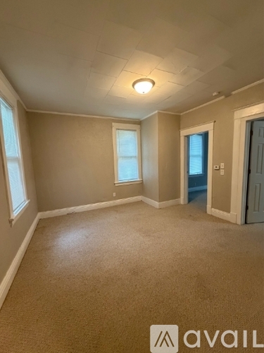 A room with beige carpet and a white ceiling with a light fixture.