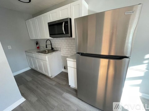 A kitchen with a stainless steel refrigerator and a microwave above the sink.