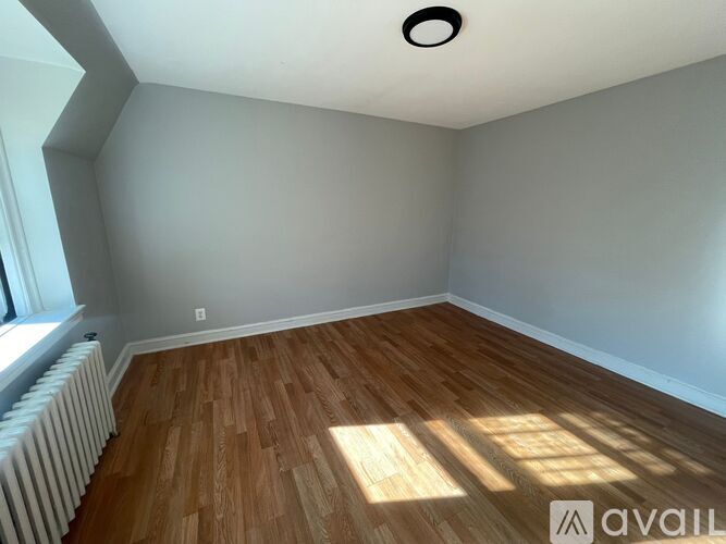 A room with wooden flooring and a window with white blinds.
