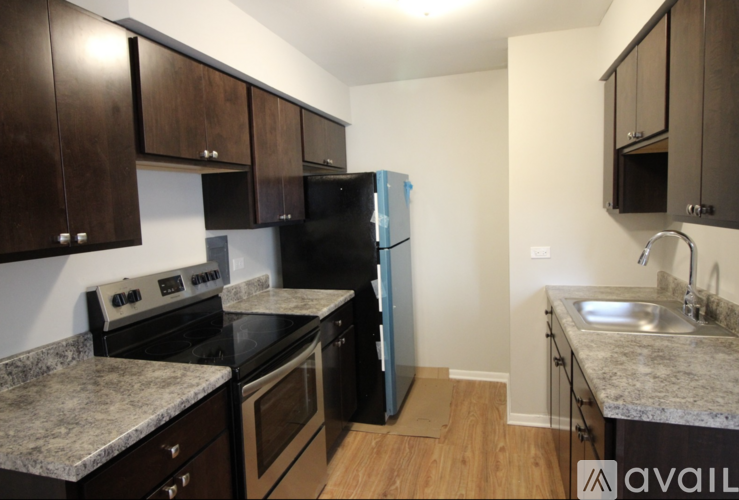 A kitchen with granite countertops and dark wood cabinets.