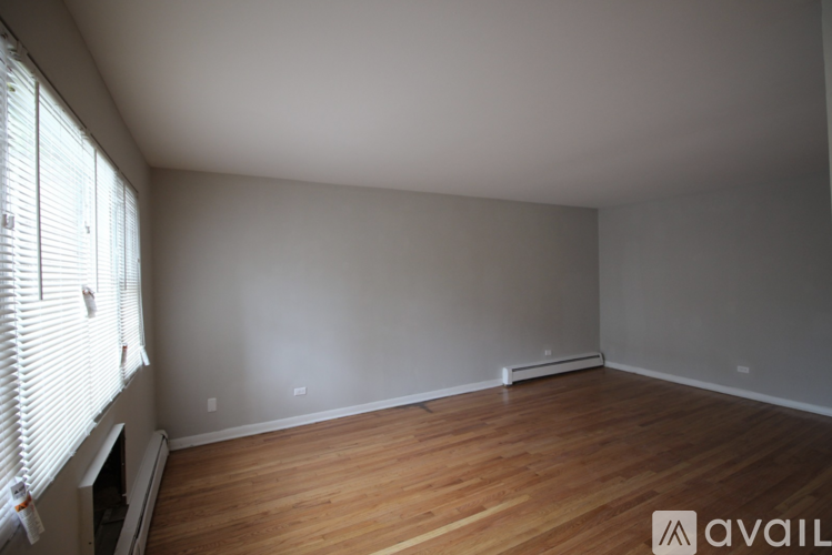 A room with wooden floors and a window with blinds.