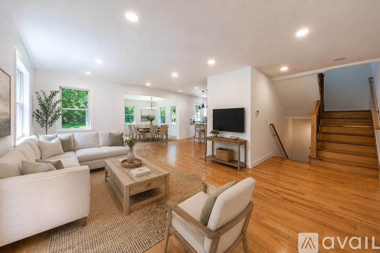 A living room with a white couch, a wooden coffee table, and a staircase.
