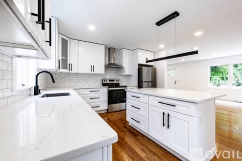 A modern kitchen with white cabinets and a marble countertop.