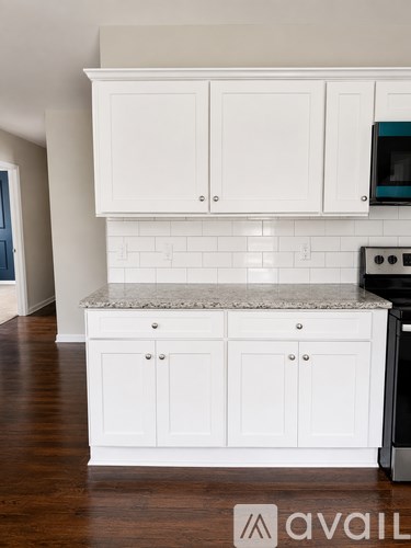 A kitchen with white cabinets and a granite countertop.
