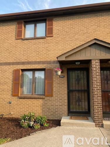 A brick house with a black door and a window with brown shutters.