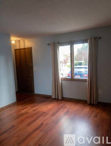 A room with wooden floors and a window with curtains.