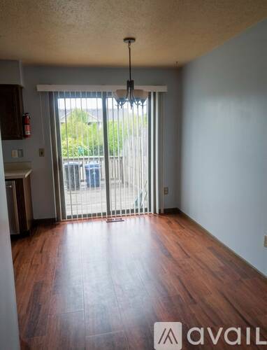 A room with wooden floors and a sliding glass door leading to a balcony.