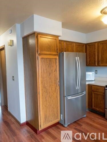 A kitchen with a refrigerator and wooden cabinets.