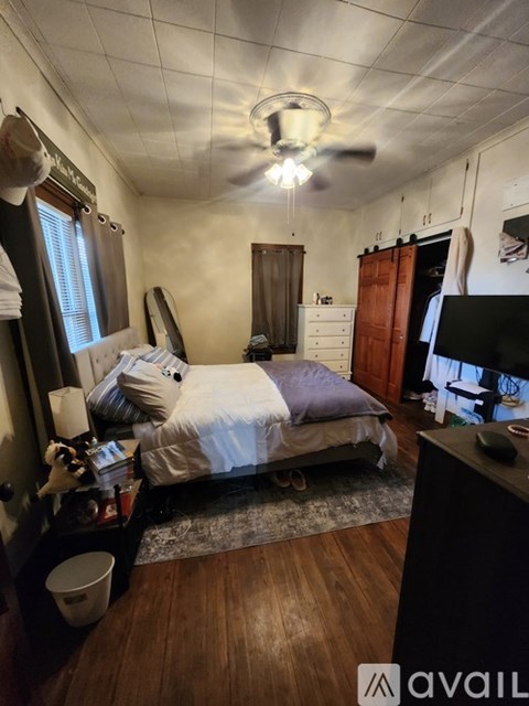 A bedroom with a bed, dresser, and ceiling fan.