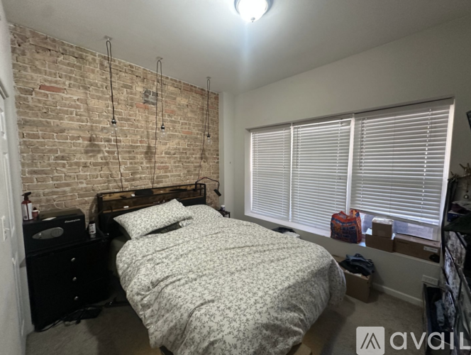 A bedroom with a brick wall and a bed with a white comforter.