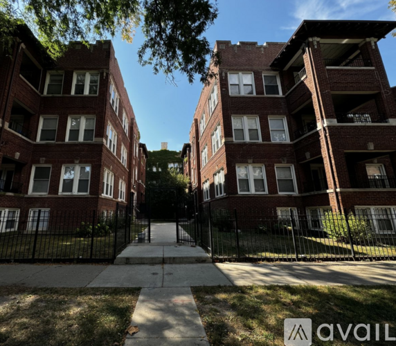 A row of red brick apartment buildings with a black fence in front.