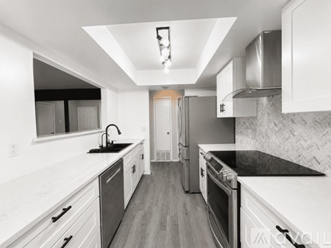 A modern kitchen with white cabinets and black countertops.