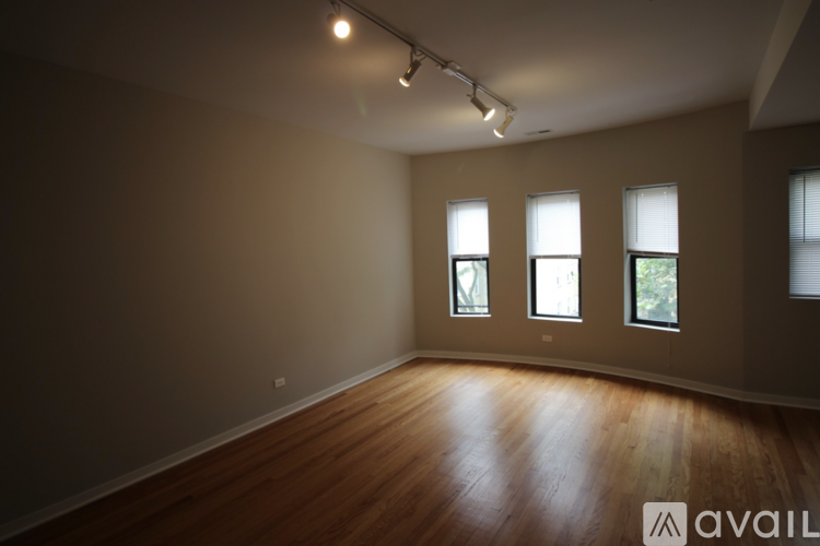A room with wooden floors and three windows.