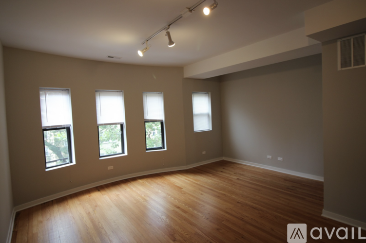 A room with wooden floors and four windows.