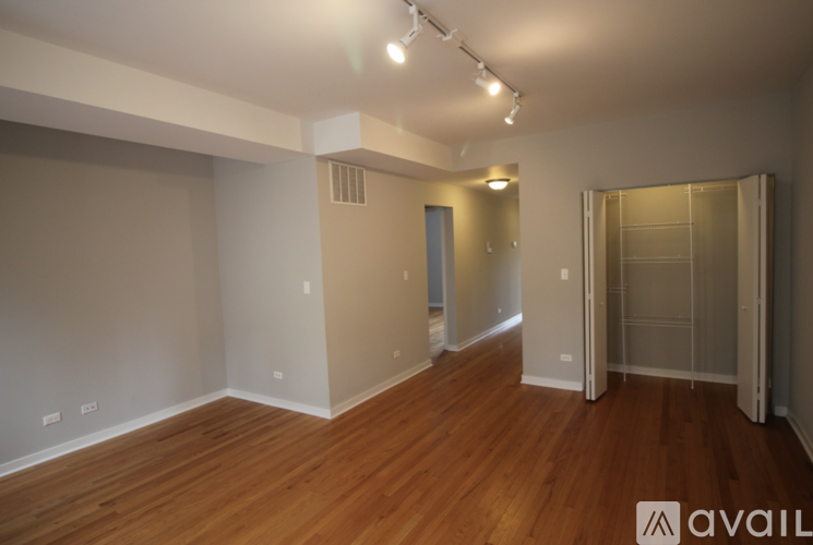 A spacious room with wooden floors and a large mirror on the wall.