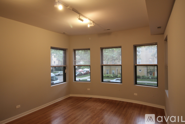 A room with wooden floors and three windows showing an outdoor view.