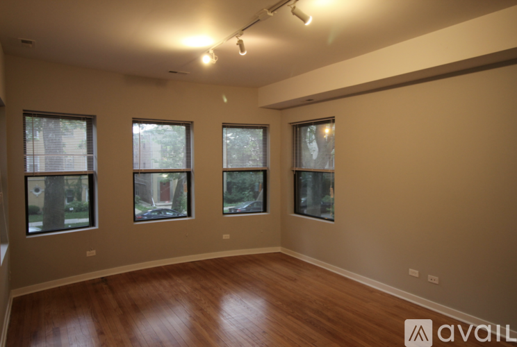 A room with wooden floors and three windows.