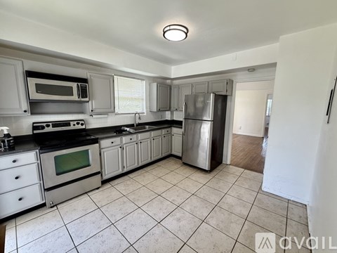 A kitchen with white cabinets and a tile floor.