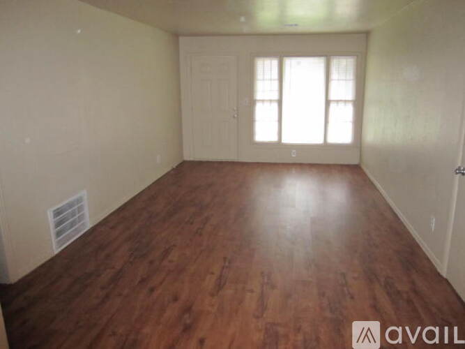A room with wooden flooring and a window with sunlight coming through.