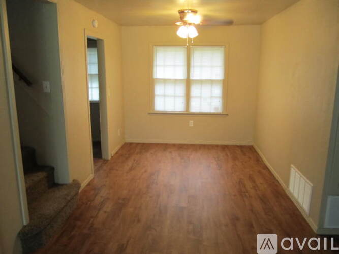 A room with wooden floors and a window with white blinds.