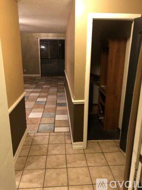 A hallway with a tiled floor and a doorway leading to another room.